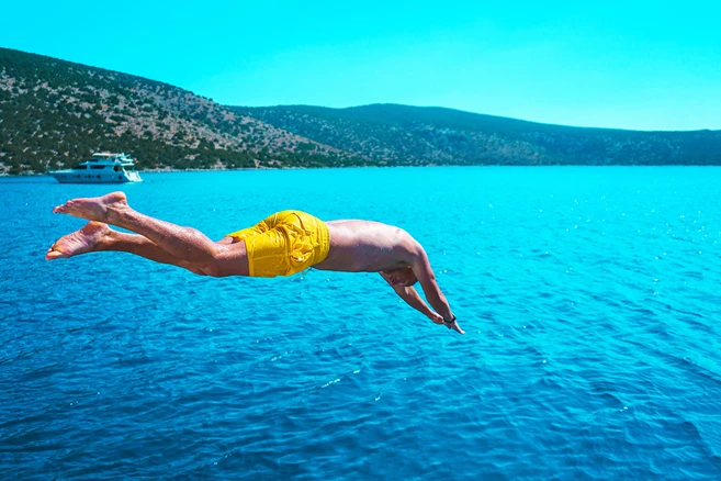 Passengers jumping from small ship into the sea